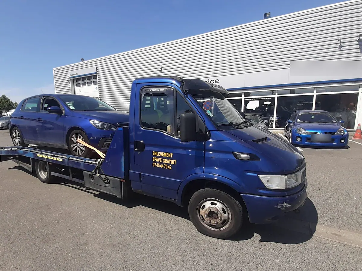 Notre camion plateau devant un garage, une voiture sanglée sur le plateau